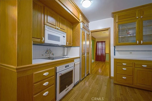 5062 Magnolia Ave, Riverside, CA 92506 - kitchen with white microwave, stainless steel oven, tile counters, backsplash, and brown cabinetry