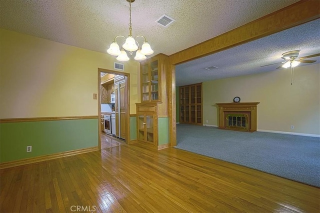 5062 Magnolia Ave, Riverside, CA 92506 - empty room featuring a textured ceiling, a fireplace, a chandelier, hardwood / wood-style floors, and baseboards
