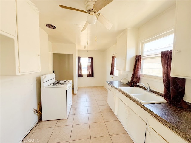 2574 W Glencrest Ave, Anaheim, CA 92801 - kitchen featuring white range with gas stovetop, a ceiling fan, light tile patterned floors, dark countertops, and white cabinets