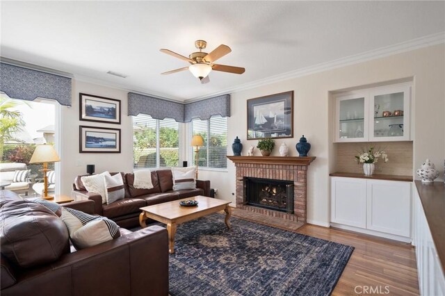 4583 Tuscani Dr, Cypress, CA 90630 - living room featuring ornamental molding, a ceiling fan, wood finished floors, and a brick fireplace