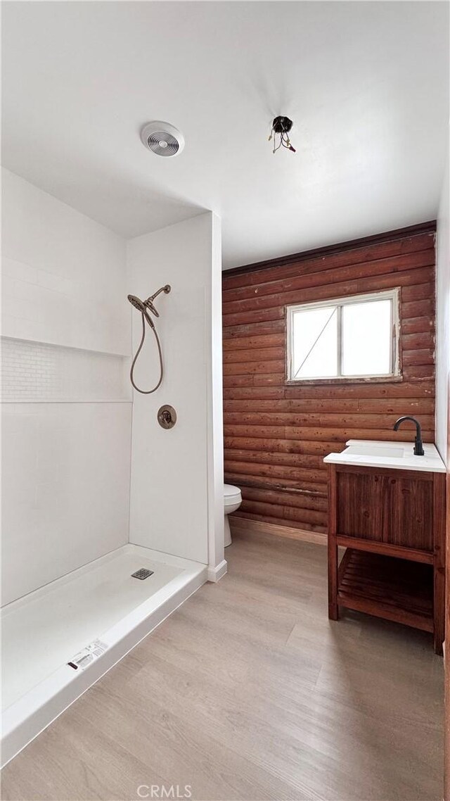 11213 Monte Vista Rd, Phelan, CA 92371 - full bathroom featuring rustic walls, a shower, toilet, wood finished floors, and a sink