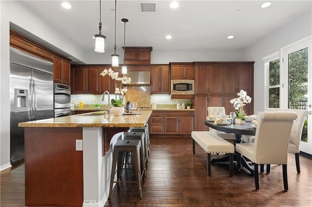 1138 Las Colinas Way, San Dimas, CA 91773 - kitchen with built in appliances, pendant lighting, a kitchen island with sink, light stone countertops, and dark wood finished floors