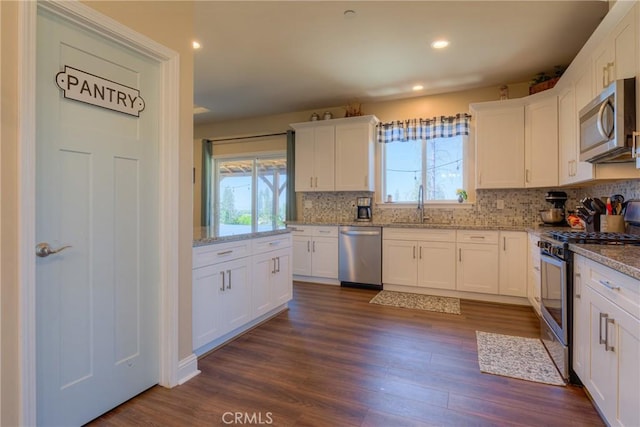 2381 Clearview Dr, Paradise, CA 95969 - kitchen featuring appliances with stainless steel finishes, decorative backsplash, white cabinetry, dark wood finished floors, and light stone counters