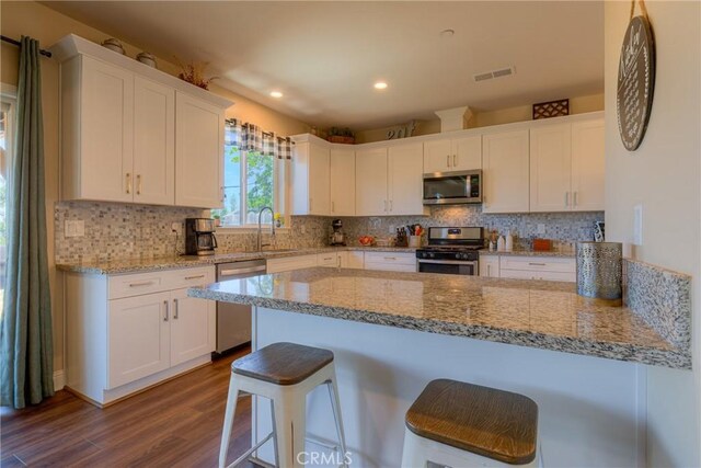 2381 Clearview Dr, Paradise, CA 95969 - kitchen with appliances with stainless steel finishes, dark wood finished floors, white cabinets, a breakfast bar area, and a sink