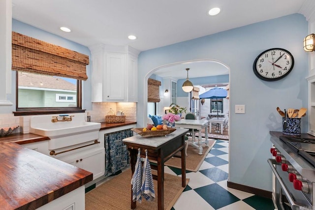 1008 S Ditmar St, Oceanside, CA 92054 - kitchen featuring light flooring, wooden counters, tasteful backsplash, arched walkways, and white cabinetry