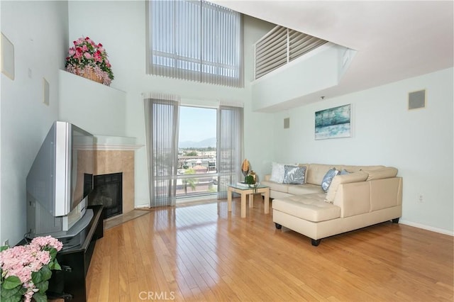580 W Main St Unit 323, Alhambra, CA 91801 - living room with hardwood / wood-style flooring, a tiled fireplace, a towering ceiling, and baseboards