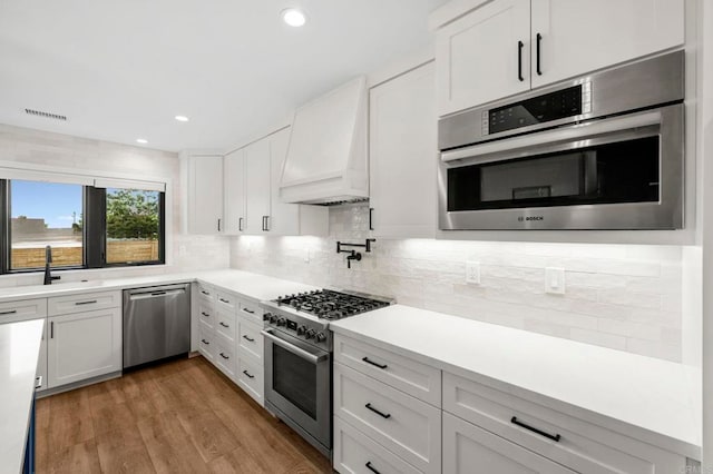 1125 Arcadia Rd, Encinitas, CA 92024 - kitchen with stainless steel appliances, custom range hood, white cabinets, decorative backsplash, and recessed lighting