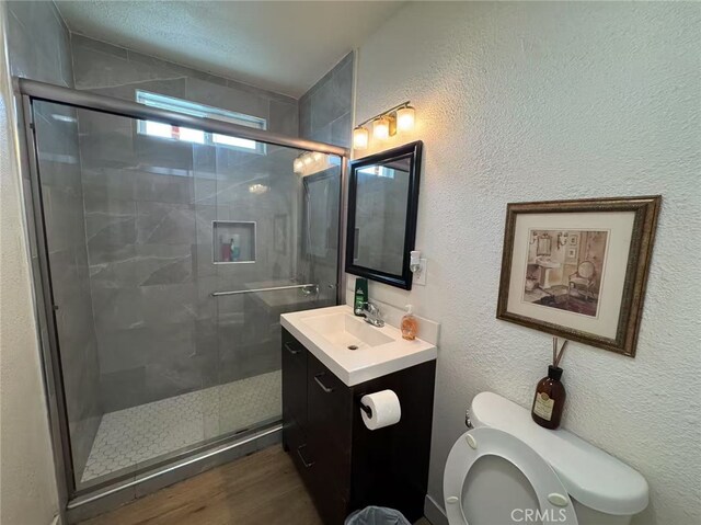951 E Elma St, Ontario, CA 91764 - bathroom featuring toilet, vanity, a shower stall, wood finished floors, and a textured wall