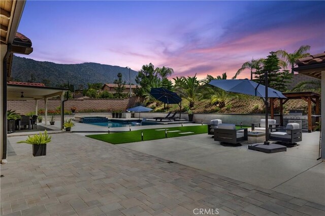288 Shorey Dr, Glendora, CA 91741 - patio terrace at dusk with an outdoor hangout area, a patio area, a mountain view, a fenced backyard, and an outdoor kitchen