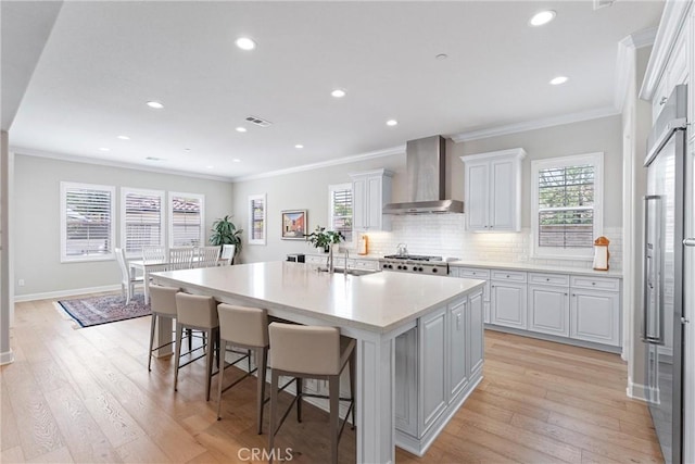 288 Shorey Dr, Glendora, CA 91741 - kitchen featuring wall chimney exhaust hood, crown molding, white cabinets, a kitchen breakfast bar, and an island with sink