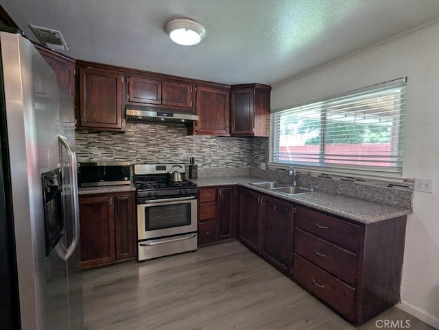 751 Glenwood Ln, Willows, CA 95988 - kitchen with appliances with stainless steel finishes, a sink, under cabinet range hood, light wood finished floors, and tasteful backsplash