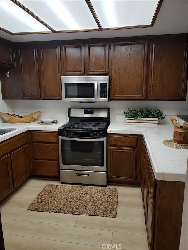 1406 Brett Pl Unit 112, San Pedro, CA 90732 - kitchen with appliances with stainless steel finishes, tile counters, and light wood-style floors