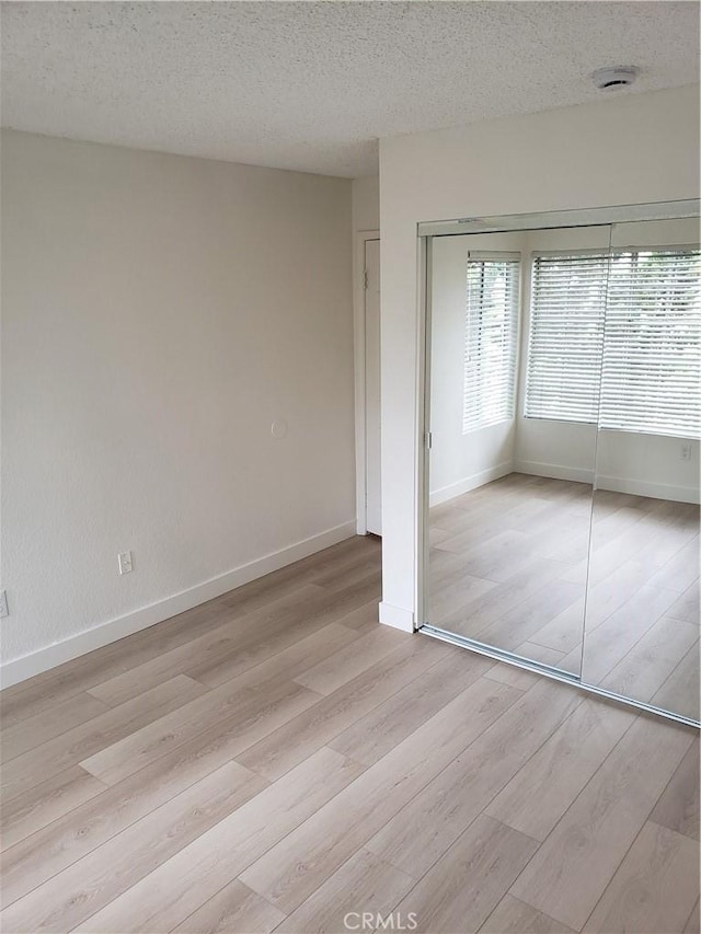 1406 Brett Pl Unit 112, San Pedro, CA 90732 - unfurnished bedroom with light wood-style floors, a closet, a textured ceiling, and baseboards