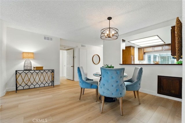 1406 Brett Pl Unit 112, San Pedro, CA 90732 - dining room with light wood finished floors, a chandelier, and a textured ceiling