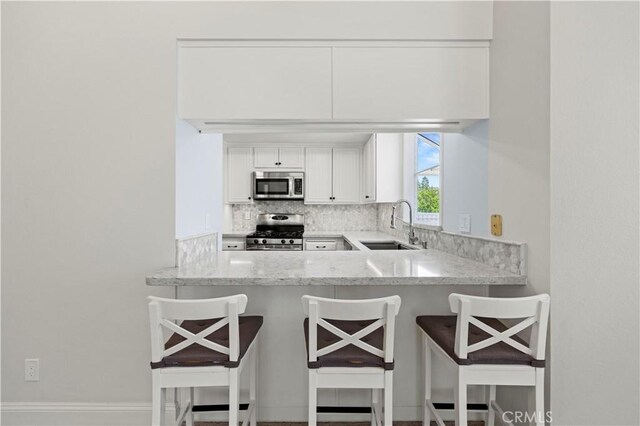 26904 Flo Ln Unit 456, Canyon Country, CA 91351 - kitchen featuring appliances with stainless steel finishes, a sink, decorative backsplash, white cabinets, and light stone counters