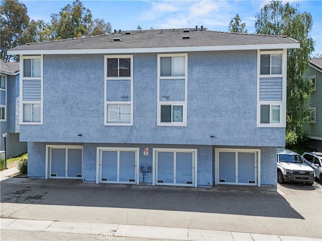 26904 Flo Ln Unit 456, Canyon Country, CA 91351 - back of property with stucco siding, a garage, and a tiled roof