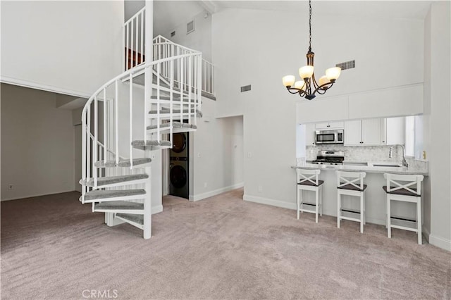 26904 Flo Ln Unit 456, Canyon Country, CA 91351 - interior space featuring appliances with stainless steel finishes, high vaulted ceiling, a chandelier, light colored carpet, and a breakfast bar
