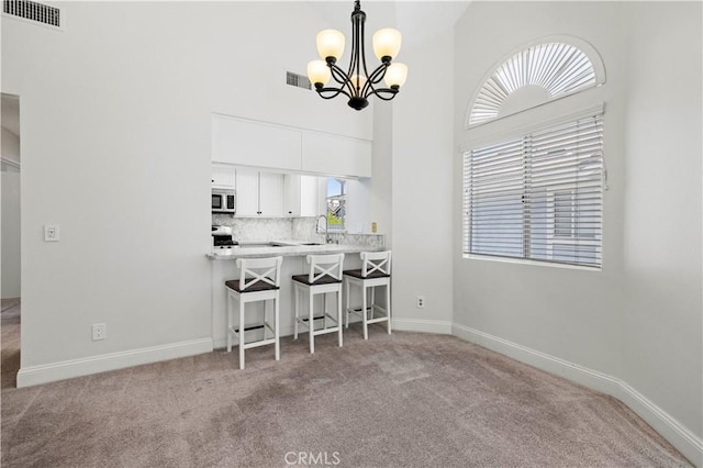 26904 Flo Ln Unit 456, Canyon Country, CA 91351 - carpeted dining room with a chandelier, a sink, a high ceiling, and baseboards