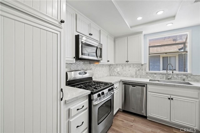 26904 Flo Ln Unit 456, Canyon Country, CA 91351 - kitchen featuring appliances with stainless steel finishes, a sink, backsplash, white cabinetry, and light wood-style flooring
