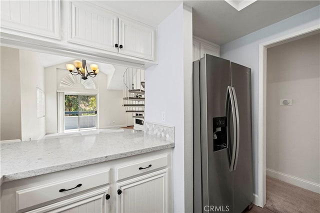 26904 Flo Ln Unit 456, Canyon Country, CA 91351 - kitchen featuring stainless steel fridge, a chandelier, white cabinetry, and light stone counters