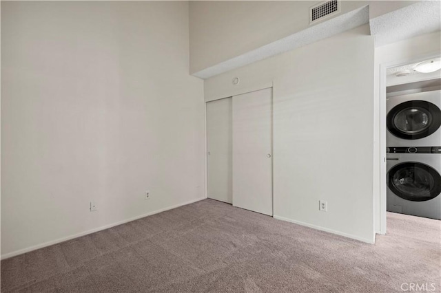 26904 Flo Ln Unit 456, Canyon Country, CA 91351 - laundry room featuring stacked washing machine and dryer, carpet flooring, and baseboards