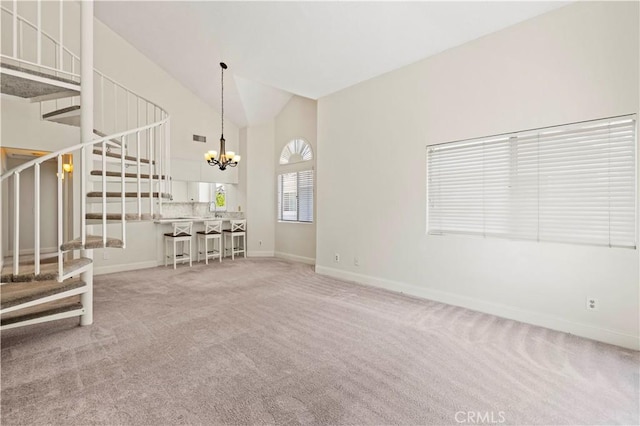 26904 Flo Ln Unit 456, Canyon Country, CA 91351 - unfurnished living room with stairs, a chandelier, baseboards, carpet flooring, and high vaulted ceiling
