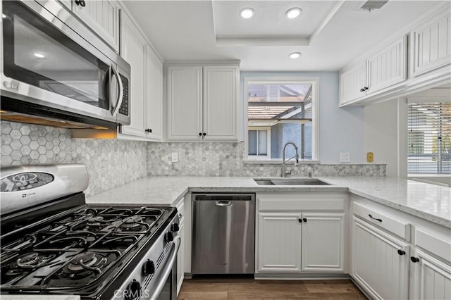 26904 Flo Ln Unit 456, Canyon Country, CA 91351 - kitchen featuring stainless steel appliances, a sink, white cabinets, decorative backsplash, and light stone countertops