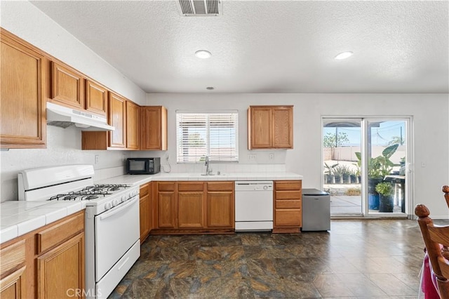 16029 White Mountain Pl, Victorville, CA 92394 - kitchen with white appliances, under cabinet range hood, tile countertops, healthy amount of natural light, and a textured ceiling
