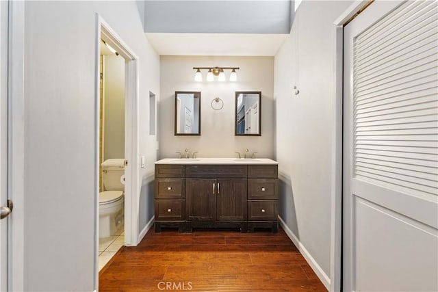 5460 White Oak Ave Unit E339, Encino, CA 91316 - bathroom featuring double vanity, toilet, wood finished floors, and baseboards
