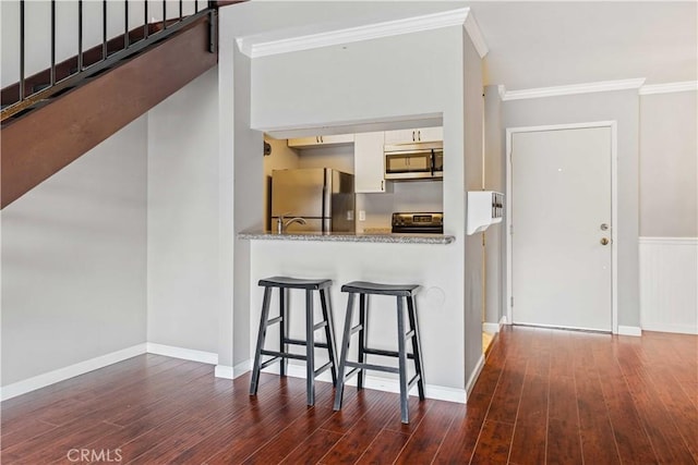 5460 White Oak Ave Unit E339, Encino, CA 91316 - kitchen with stainless steel appliances, wood finished floors, crown molding, a kitchen bar, and white cabinets