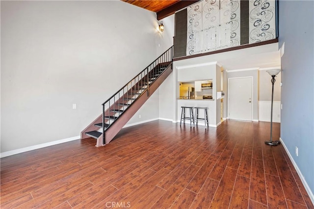 5460 White Oak Ave Unit E339, Encino, CA 91316 - unfurnished living room with stairway, baseboards, wood finished floors, a high ceiling, and wood ceiling with exposed beams