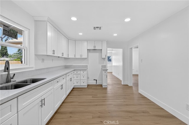 401 Cypress St, Bakersfield, CA 93304 - kitchen with a sink, recessed lighting, white cabinetry, light wood-type flooring, and baseboards