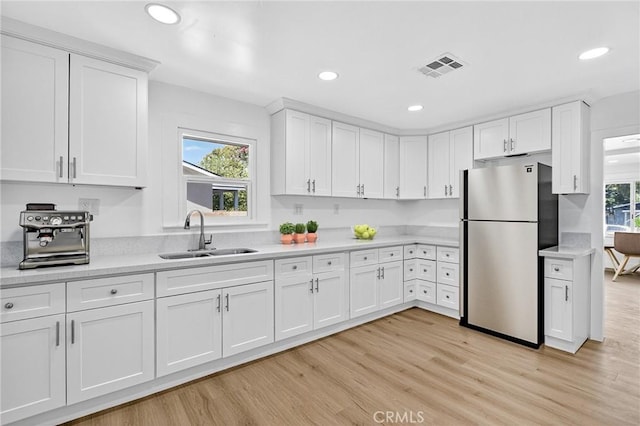 401 Cypress St, Bakersfield, CA 93304 - kitchen with freestanding refrigerator, light countertops, white cabinets, light wood finished floors, and recessed lighting