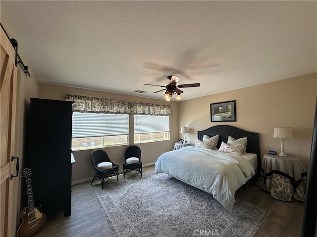 2408 Driftwood Dr, Rosamond, CA 93560 - bedroom featuring a barn door, wood finished floors, baseboards, a ceiling fan, and a textured ceiling