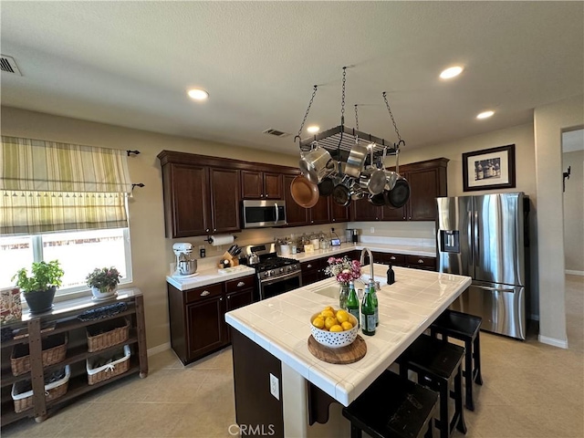 2408 Driftwood Dr, Rosamond, CA 93560 - kitchen featuring appliances with stainless steel finishes, a sink, tile countertops, dark brown cabinets, and recessed lighting