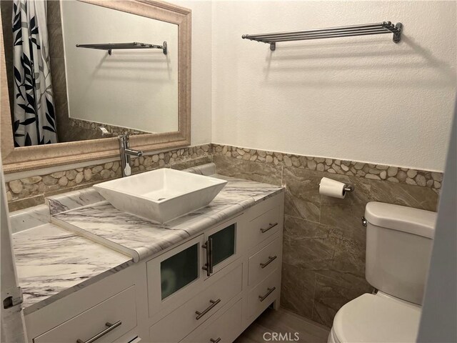 774 Josie St, Blythe, CA 92225 - full bathroom featuring tile walls, toilet, vanity, and a wainscoted wall