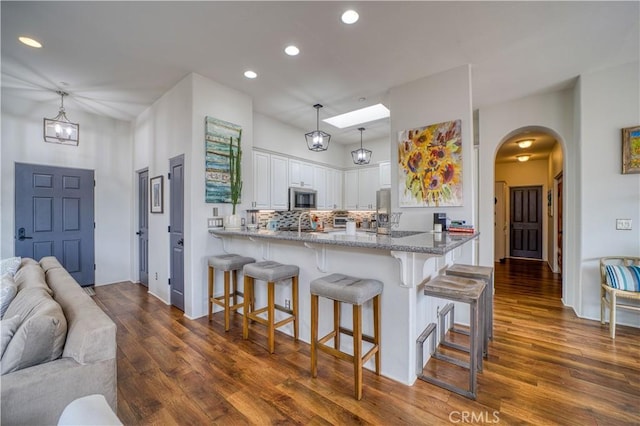 516 Stoneridge Dr, San Luis Obispo, CA 93401 - kitchen featuring white cabinetry, recessed lighting, a kitchen bar, arched walkways, and dark wood-style flooring