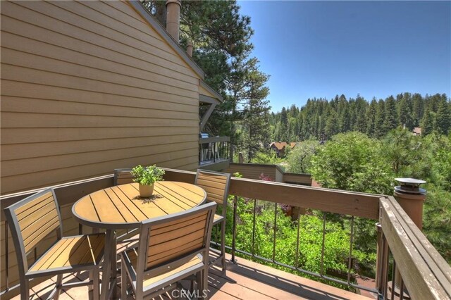 27657 Peninsula Dr Unit 131, Lake Arrowhead, CA 92352 - wooden terrace with outdoor dining area and a wooded view