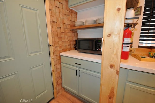 40122 Highland Rd, Big Bear Lake, CA 92315 - kitchen view of stainless steel microwave, open shelves, a fire extinguisher, light countertops, and green cabinetry