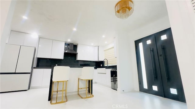 7401 Liberty Ave, Corona, CA 92881 - kitchen featuring wall chimney exhaust hood, white cabinetry, a kitchen bar, modern cabinets, and decorative backsplash