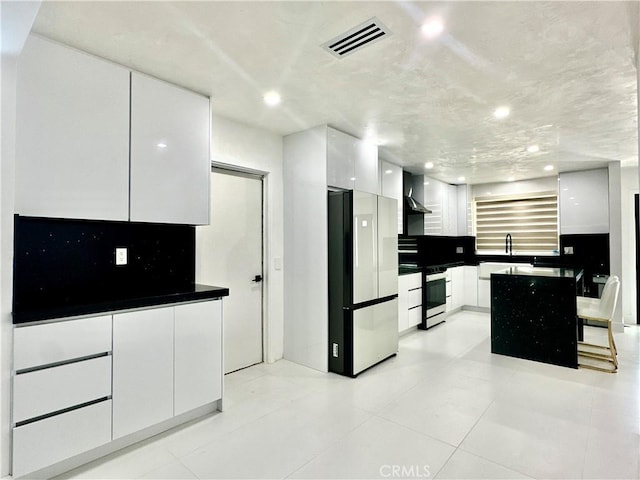 7401 Liberty Ave, Corona, CA 92881 - kitchen featuring stainless steel range with electric cooktop, modern cabinets, wall chimney exhaust hood, freestanding refrigerator, and white cabinets