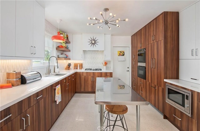 16827 Bircher St, Granada Hills, CA 91344 - kitchen featuring modern cabinets, stainless steel microwave, backsplash, a chandelier, and light countertops