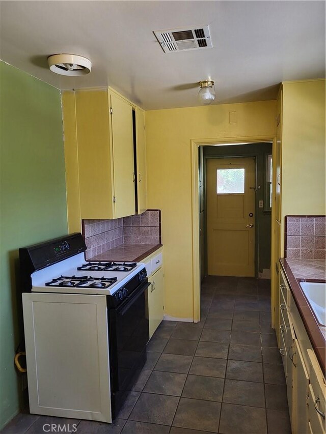 253 S Franklin St, Hemet, CA 92543 - kitchen featuring gas range oven, backsplash, dark tile patterned flooring, and cream cabinets