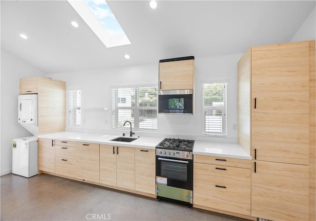 17435 Lassen St, Northridge, CA 91325 - kitchen with light brown cabinetry, stainless steel appliances, a sink, estacked washer and dryer, and a skylight