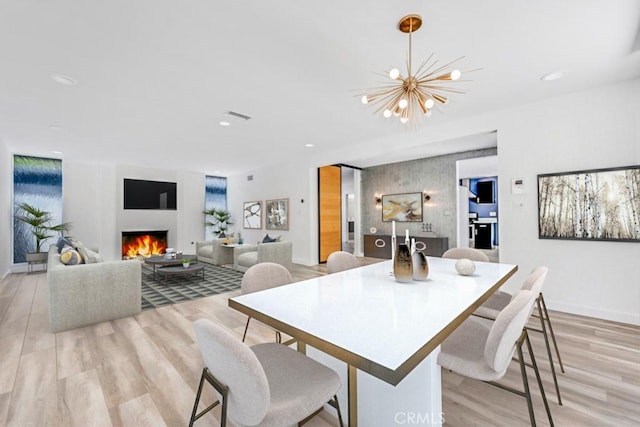 11230 Dilling St, Studio City, CA 91602 - dining room featuring a warm lit fireplace, light wood-style flooring, a chandelier, recessed lighting, and baseboards