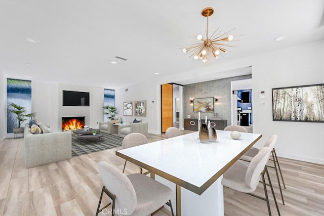 11230 Dilling St, Studio City, CA 91602 - dining space featuring a warm lit fireplace, light wood finished floors, a chandelier, recessed lighting, and baseboards