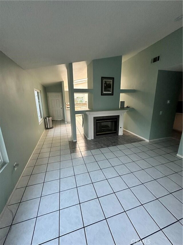 618 Award Dr, Colton, CA 92324 - unfurnished living room featuring healthy amount of natural light, light tile patterned floors, a glass covered fireplace, a textured ceiling, and baseboards