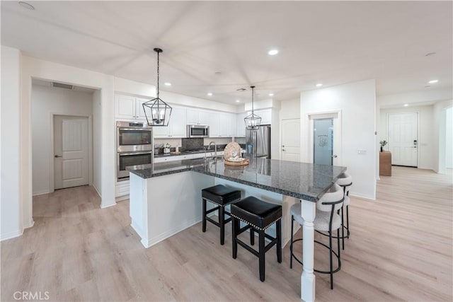 6940 Lagoon Ct, Jurupa Valley, CA 91752 - kitchen featuring stainless steel appliances, white cabinetry, light wood finished floors, a large island with sink, and recessed lighting