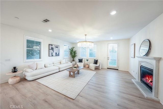 6940 Lagoon Ct, Jurupa Valley, CA 91752 - living room with recessed lighting, light wood-style floors, a glass covered fireplace, and a chandelier