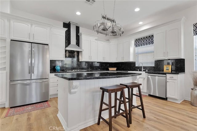 19344 Macklin St, Apple Valley, CA 92308 - kitchen with appliances with stainless steel finishes, wall chimney range hood, a kitchen island, light wood-style flooring, and white cabinetry